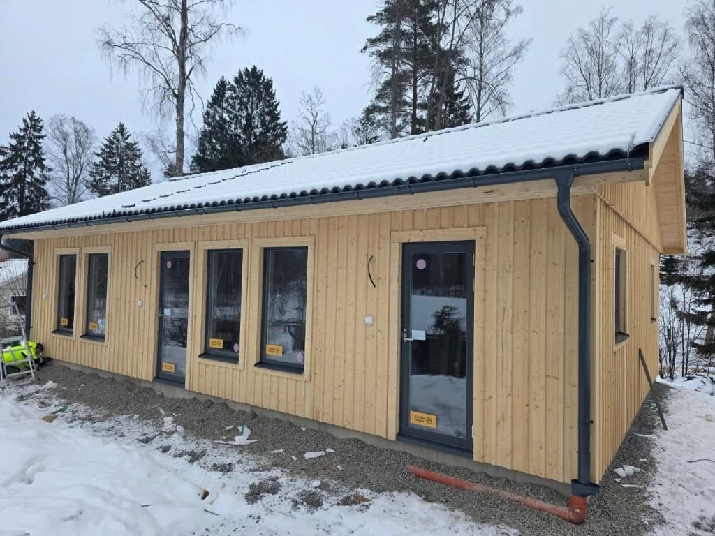 Villa under slutfas i vinterlandskap med stora fönsterpartier
